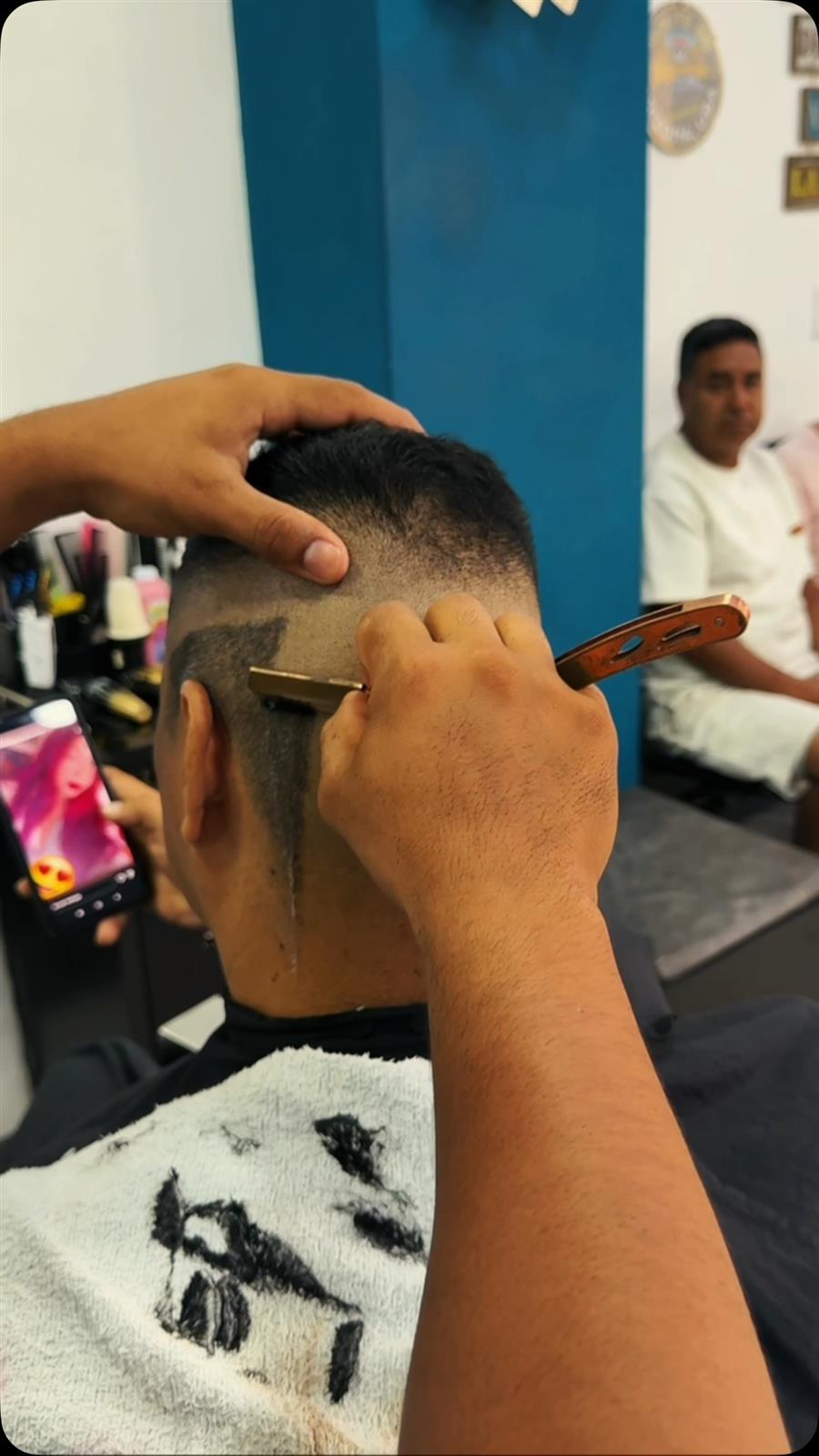 Barbero marcando un diseño con navaja en un corte degradado